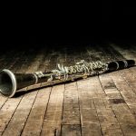 clarinete-preto-de-madeira-jaz-num-palco-marrom-o-vento-negro-se-deita-sobre-um-chão-no-escuro-169596026